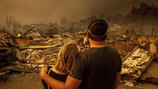 Megan Mantia, left, and her boyfriend Thomas, return to Mantia's fire-damaged home after the Eaton Fire swept through Jan. 8, 2025 in Altadena, Calif. (AP Photo/Ethan Swope)